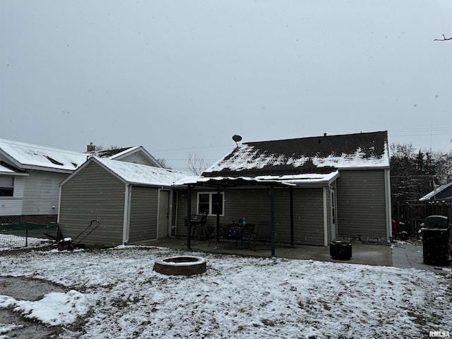 snow covered back of property featuring an outdoor fire pit