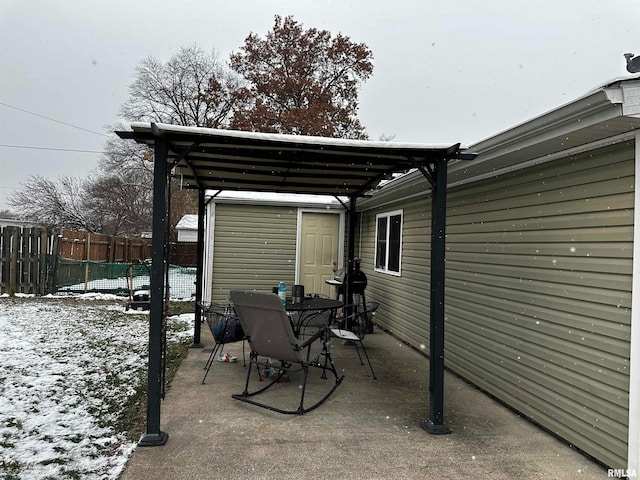 snow covered patio featuring a shed