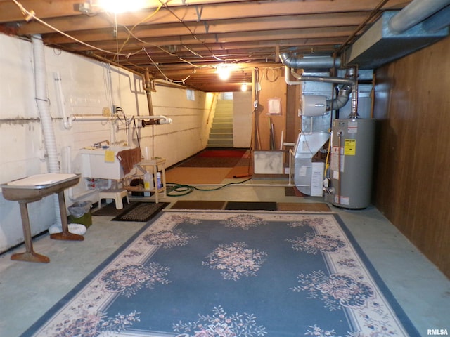 basement featuring water heater and wood walls