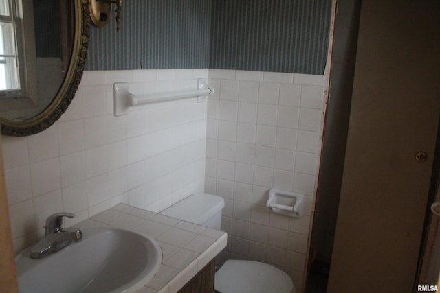 bathroom with toilet, tile walls, and sink