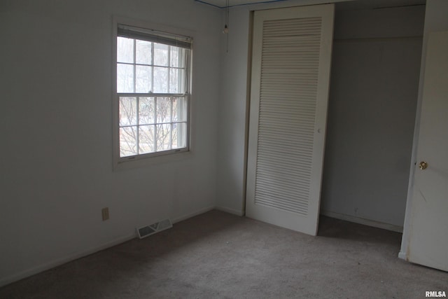 unfurnished bedroom featuring light carpet and a closet