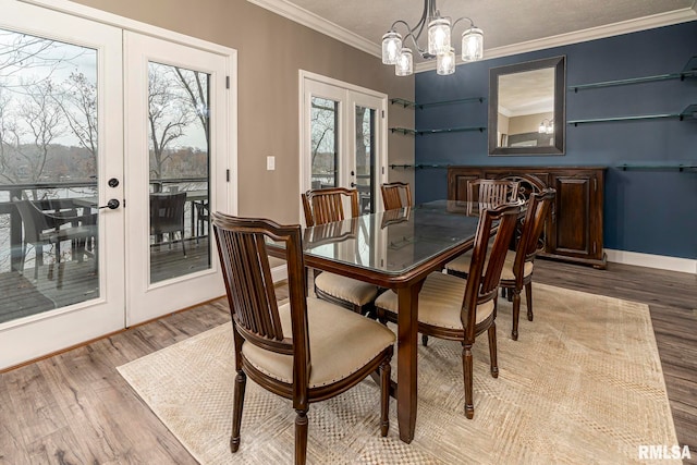 dining room with french doors, hardwood / wood-style flooring, an inviting chandelier, and ornamental molding