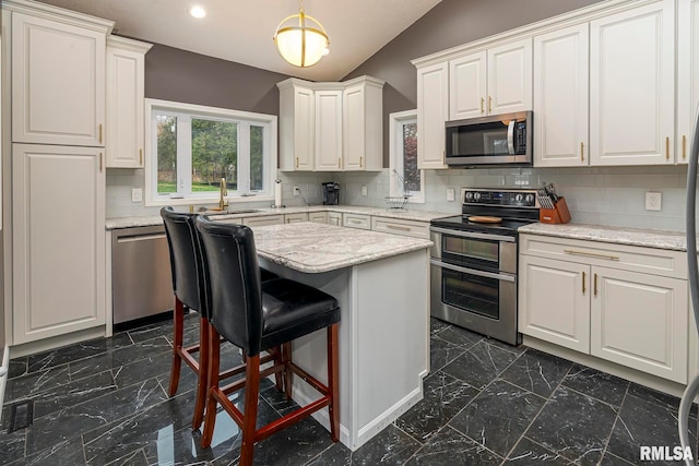 kitchen with backsplash, a kitchen island, stainless steel appliances, and vaulted ceiling