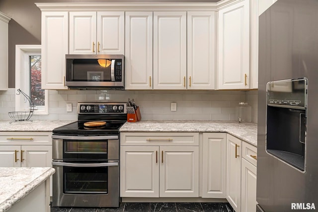 kitchen with appliances with stainless steel finishes, tasteful backsplash, light stone counters, and white cabinetry