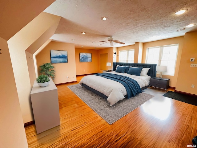 bedroom with a textured ceiling, light hardwood / wood-style flooring, and ceiling fan