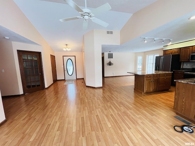 kitchen featuring a center island, black appliances, vaulted ceiling, light hardwood / wood-style flooring, and light stone countertops