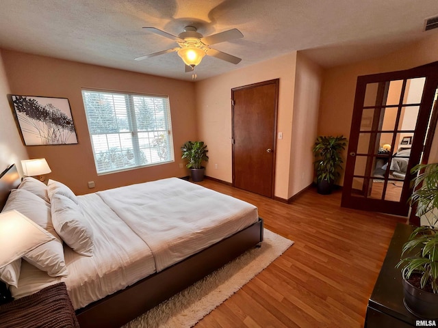 bedroom featuring hardwood / wood-style flooring, ceiling fan, and a textured ceiling