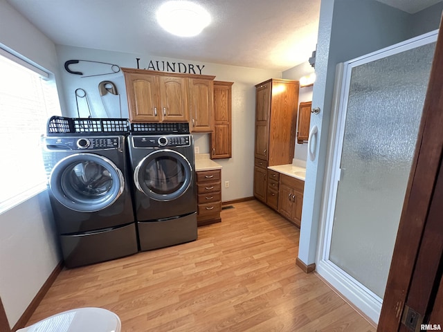 laundry area featuring separate washer and dryer, cabinets, and light wood-type flooring