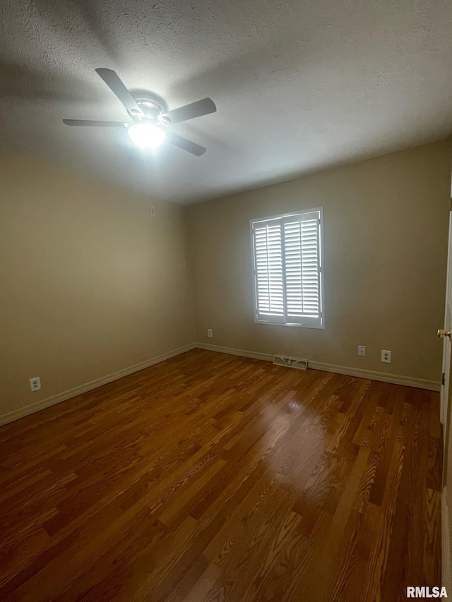 empty room with dark hardwood / wood-style floors, ceiling fan, and a textured ceiling