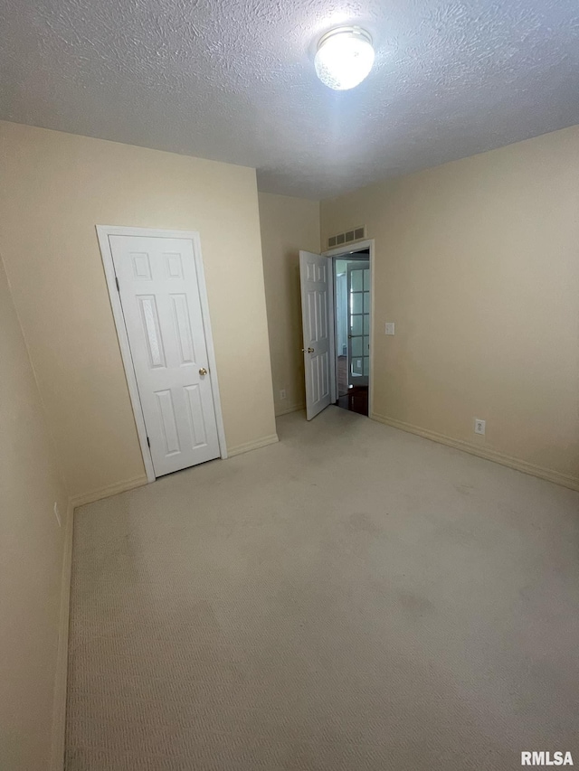 unfurnished room featuring carpet flooring and a textured ceiling