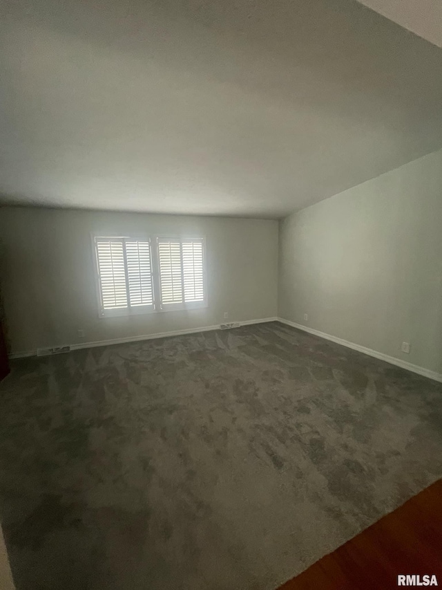 unfurnished room featuring dark carpet