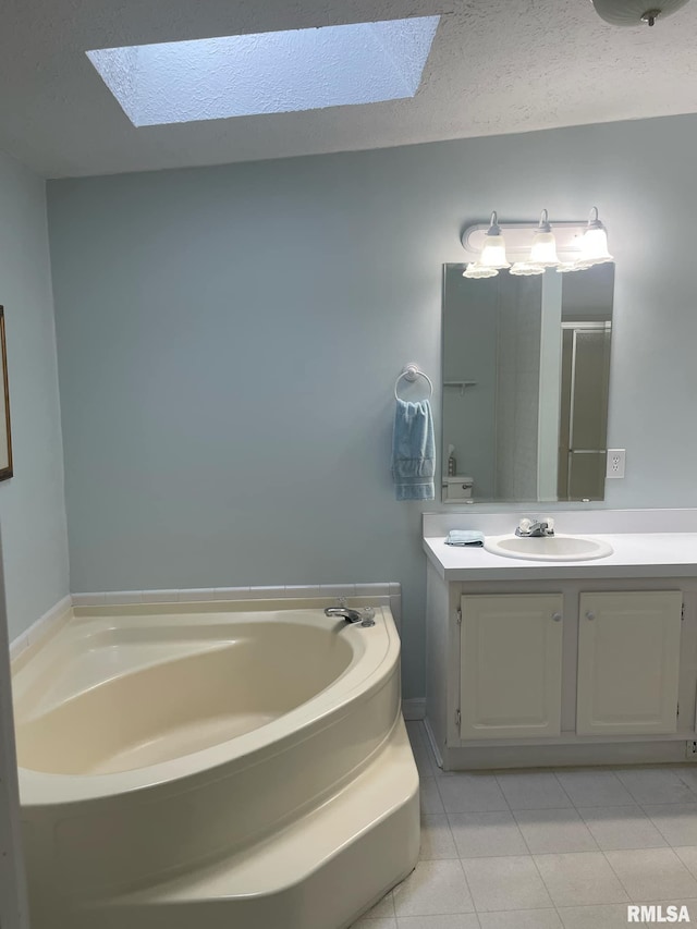 bathroom with tile patterned flooring, a tub to relax in, vanity, and a skylight