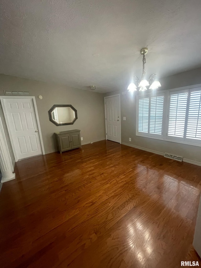 interior space with a chandelier, a textured ceiling, and dark hardwood / wood-style floors