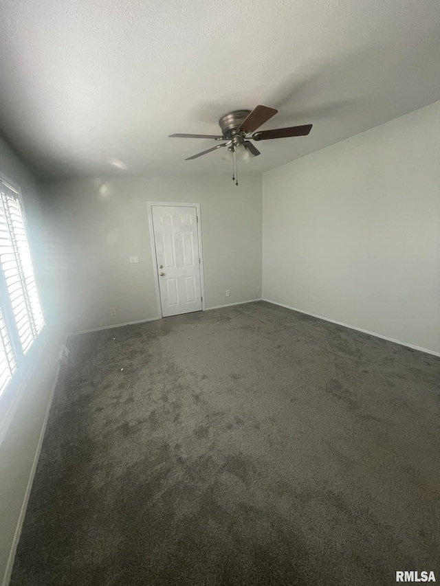 spare room with dark colored carpet, a textured ceiling, and ceiling fan