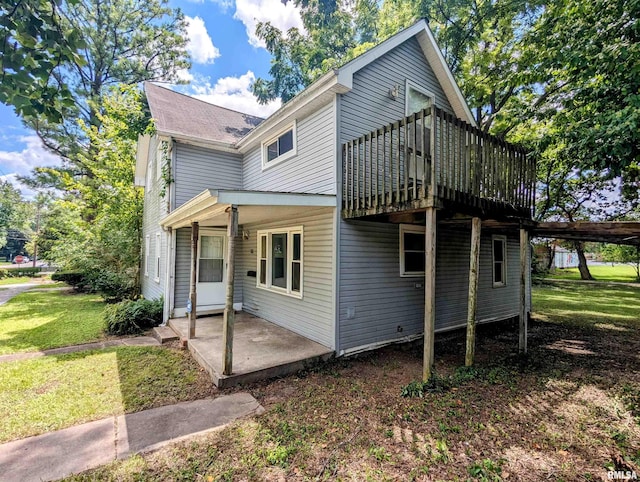 exterior space featuring a wooden deck, a patio area, and a lawn