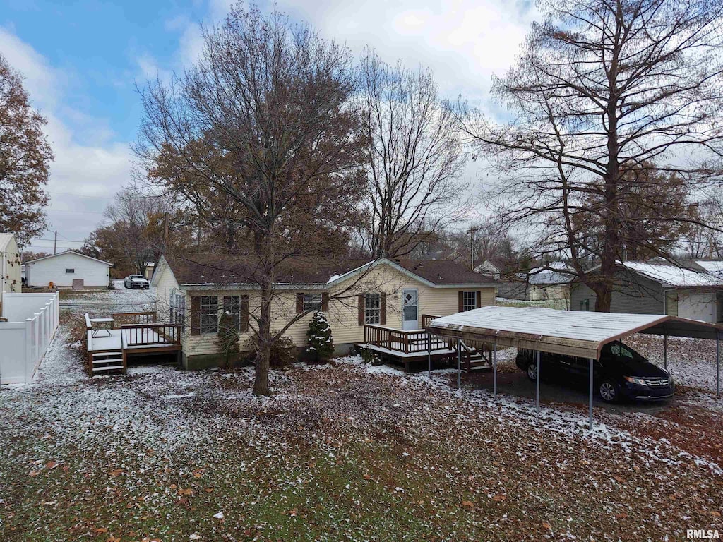 snow covered property featuring a wooden deck and a carport