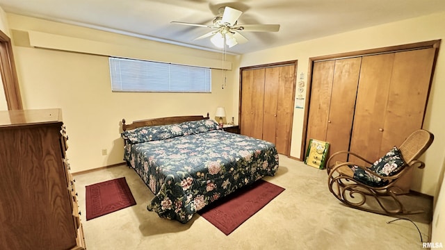 carpeted bedroom with ceiling fan and two closets