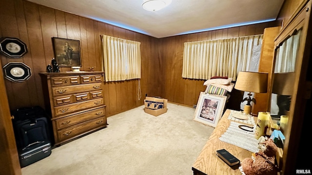 sitting room featuring light colored carpet and wooden walls