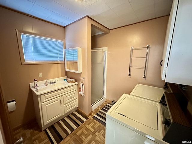 bathroom with washer and clothes dryer, vanity, parquet flooring, and a shower with door