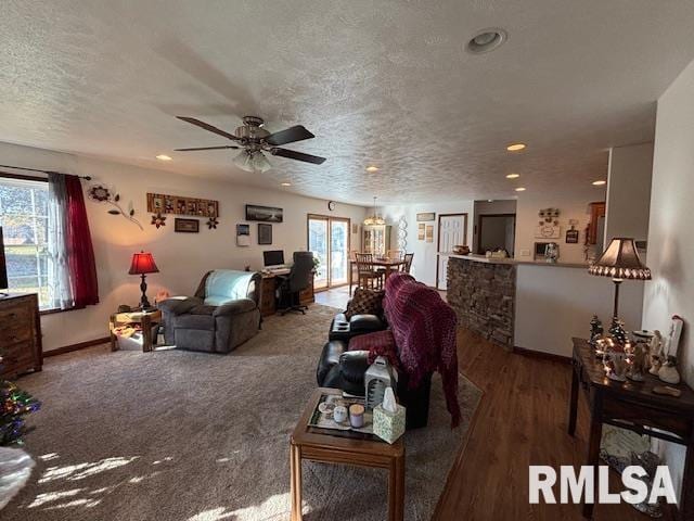 living room featuring wood-type flooring, a textured ceiling, ceiling fan, and a healthy amount of sunlight