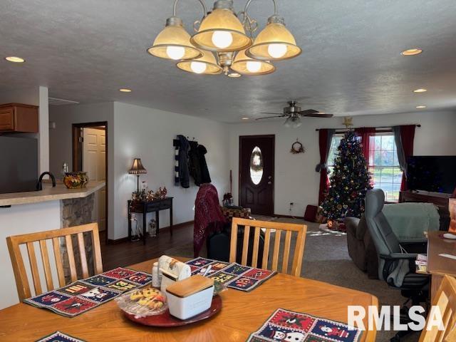 dining area with a textured ceiling and ceiling fan with notable chandelier