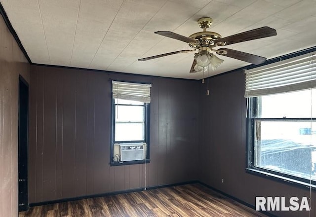 spare room featuring dark hardwood / wood-style floors, ceiling fan, wooden walls, and cooling unit