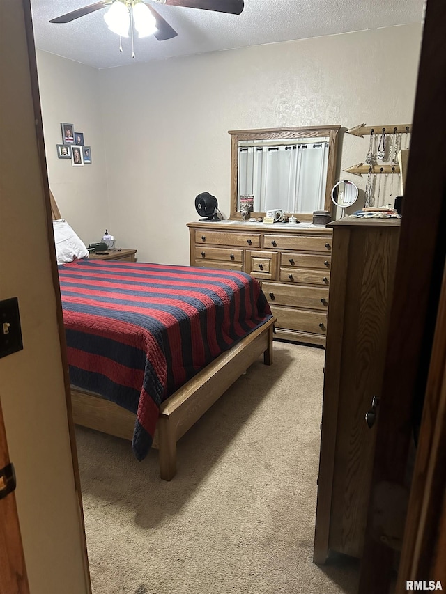 bedroom featuring ceiling fan, light colored carpet, and a textured ceiling