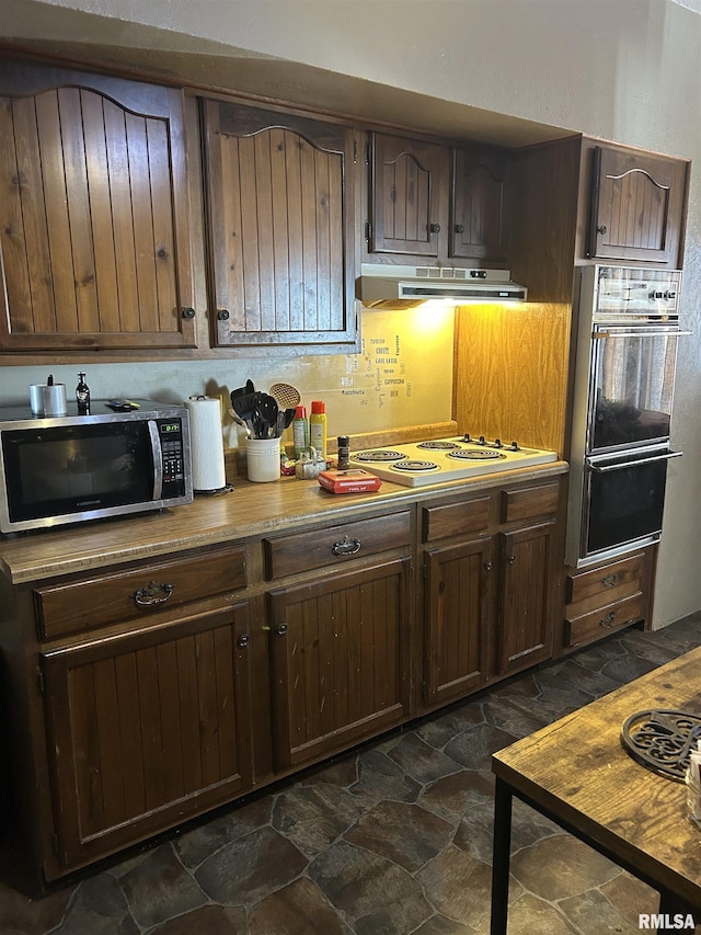 kitchen with tasteful backsplash, dark brown cabinetry, ventilation hood, white cooktop, and double oven