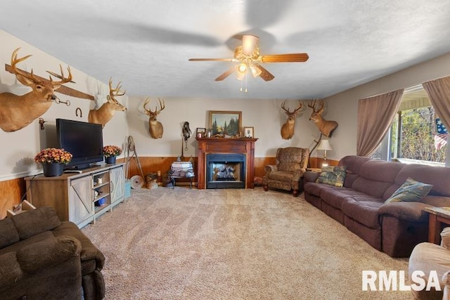 carpeted living room featuring ceiling fan and wood walls