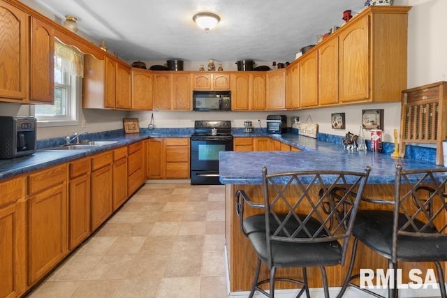 kitchen featuring black appliances, sink, light tile patterned floors, kitchen peninsula, and a breakfast bar area