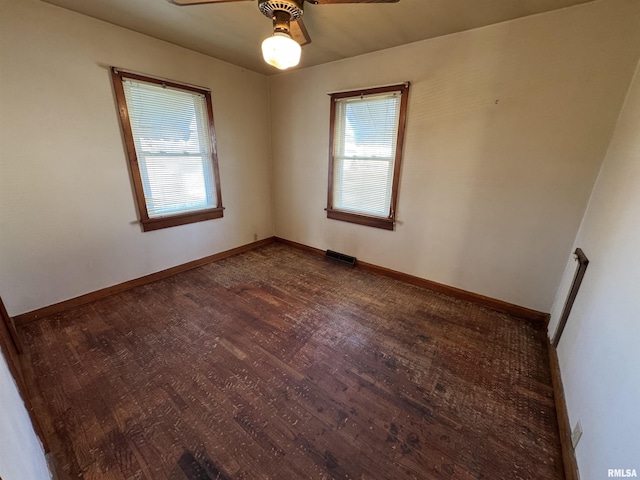 empty room with ceiling fan, plenty of natural light, and dark wood-type flooring