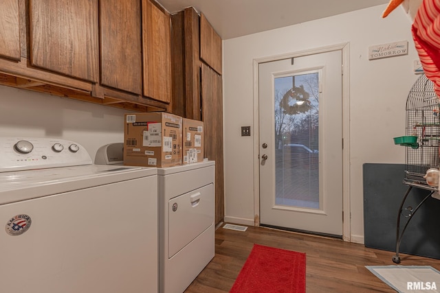 washroom featuring washing machine and dryer, dark hardwood / wood-style flooring, and cabinets