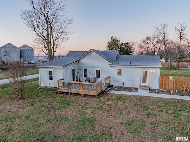 back house at dusk with a yard and a wooden deck