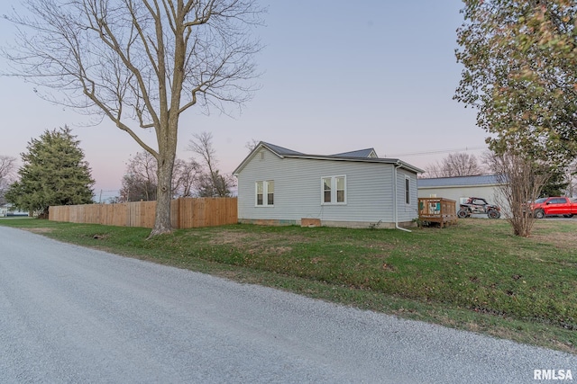 property exterior at dusk with a yard and a deck