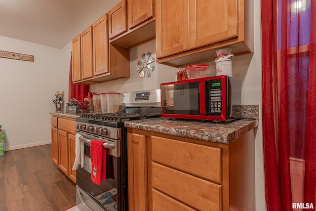 kitchen with stainless steel gas stove and dark wood-type flooring