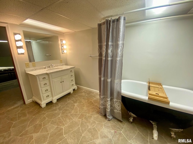 bathroom with a paneled ceiling, vanity, and a bathing tub