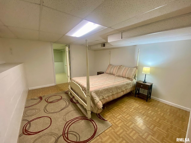 bedroom with light parquet flooring and a drop ceiling