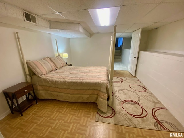 bedroom featuring light parquet flooring and a drop ceiling