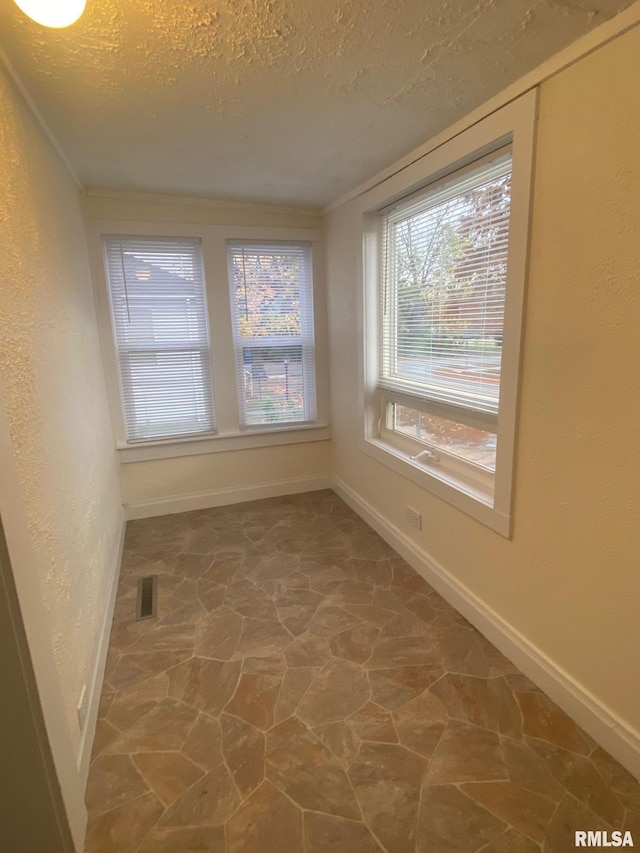 spare room featuring a textured ceiling and crown molding