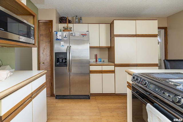 kitchen featuring white cabinets, stainless steel appliances, and a textured ceiling