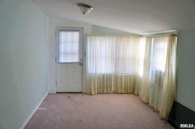 carpeted empty room with vaulted ceiling