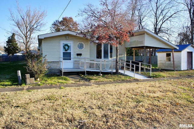 view of front of house featuring a front lawn, a deck, and a storage shed