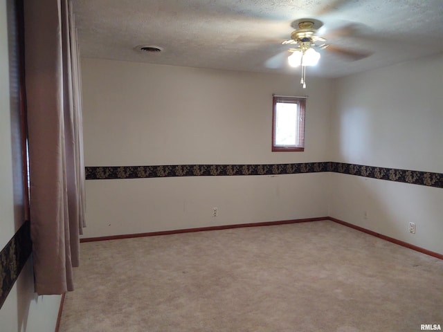 carpeted empty room with ceiling fan and a textured ceiling