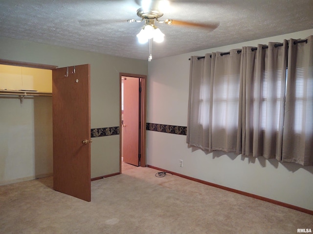 unfurnished bedroom featuring ceiling fan, a closet, light colored carpet, and a textured ceiling