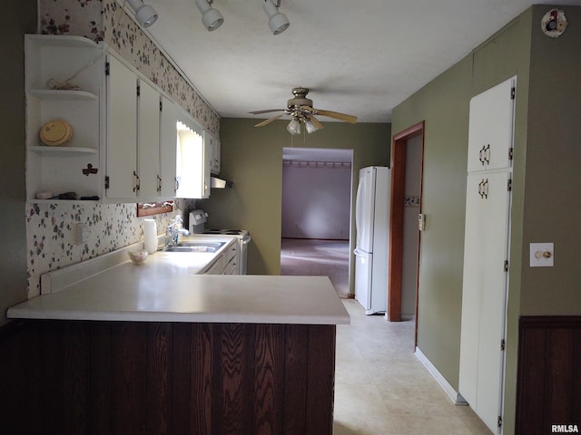 kitchen featuring white cabinetry, sink, kitchen peninsula, white appliances, and light tile patterned flooring