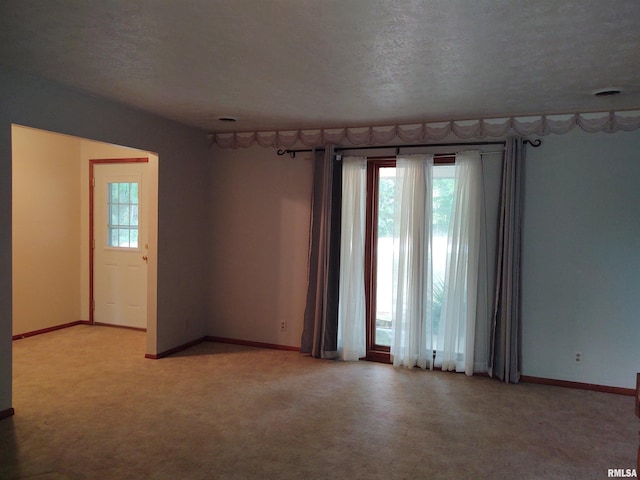 unfurnished room featuring a textured ceiling, a wealth of natural light, and light carpet