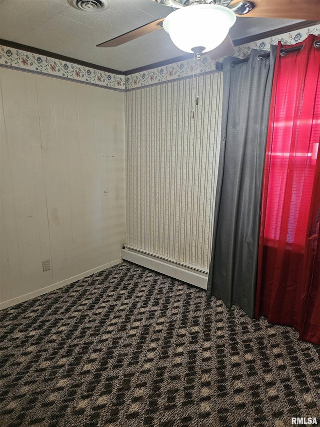 spare room with dark colored carpet, baseboard heating, and ceiling fan