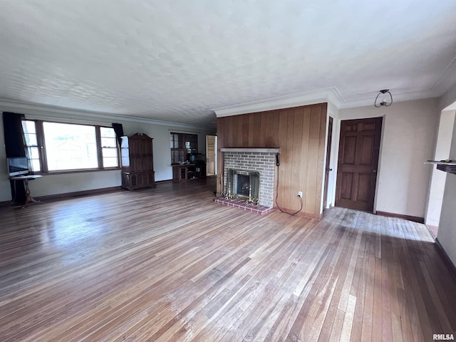 unfurnished living room with hardwood / wood-style floors, crown molding, and a fireplace