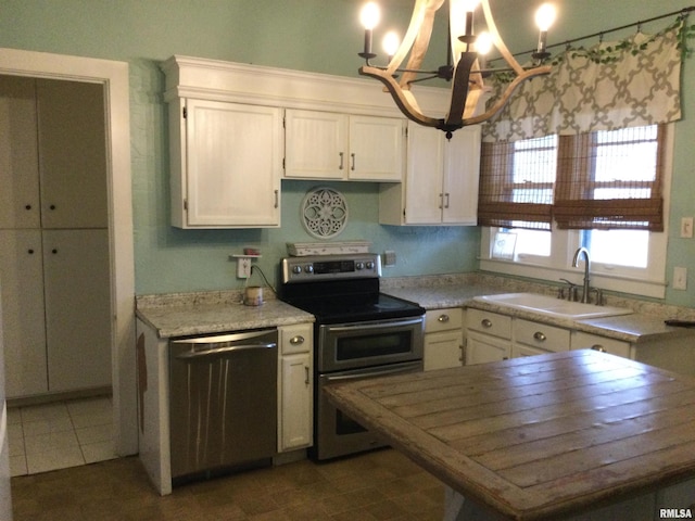 kitchen featuring white cabinets, sink, appliances with stainless steel finishes, and a chandelier