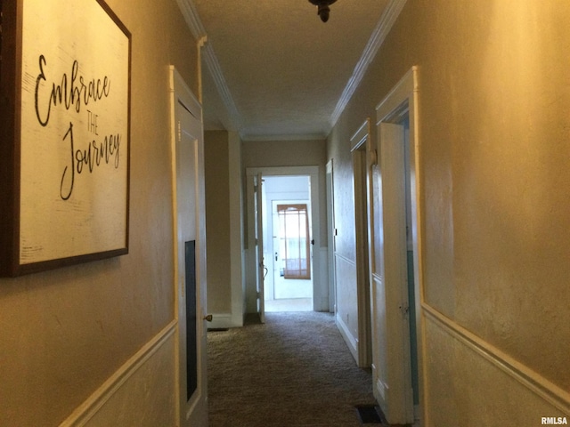 corridor featuring dark colored carpet and ornamental molding